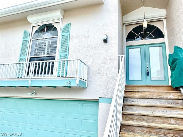 property entrance with french doors, a balcony, and stucco siding