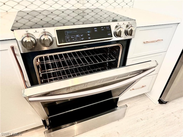 details with white cabinets, decorative backsplash, and wood finished floors