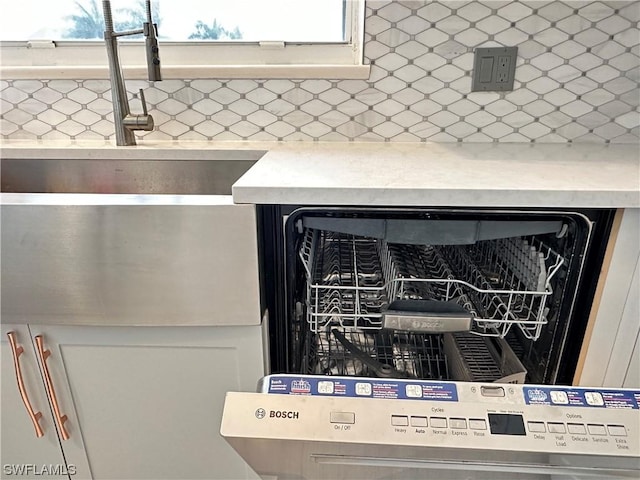 details featuring tasteful backsplash, light countertops, and dishwasher