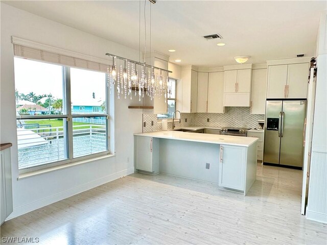 kitchen featuring tasteful backsplash, stainless steel appliances, white cabinetry, and hanging light fixtures