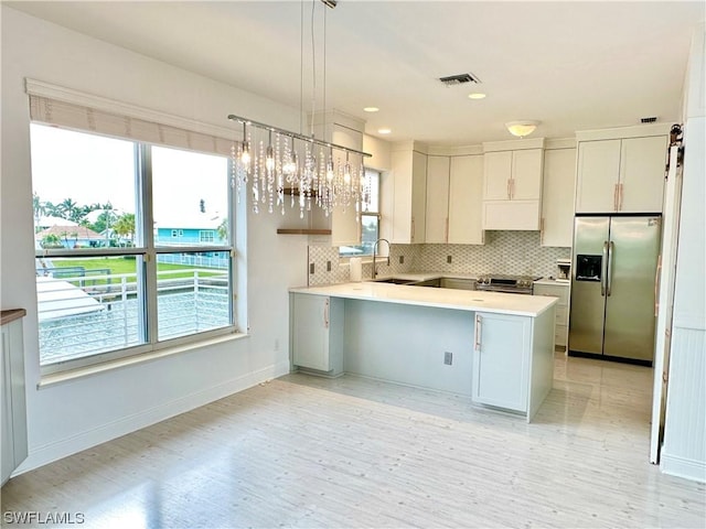 kitchen with stainless steel appliances, light countertops, visible vents, backsplash, and a peninsula