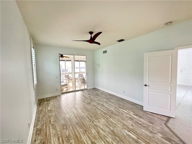 unfurnished room with a ceiling fan, wood finished floors, visible vents, and baseboards