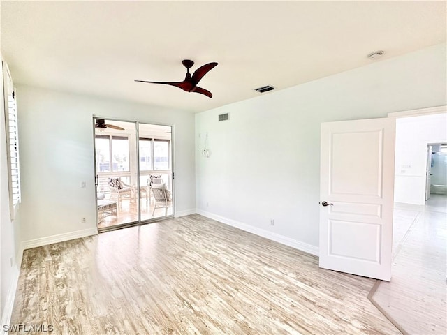 empty room featuring light wood-style floors, ceiling fan, visible vents, and baseboards