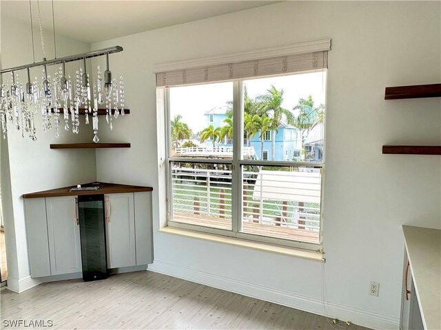 interior space featuring pendant lighting, beverage cooler, a healthy amount of sunlight, and an inviting chandelier