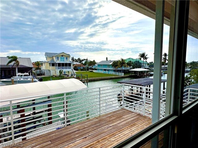 dock area with a water view, a balcony, and a residential view