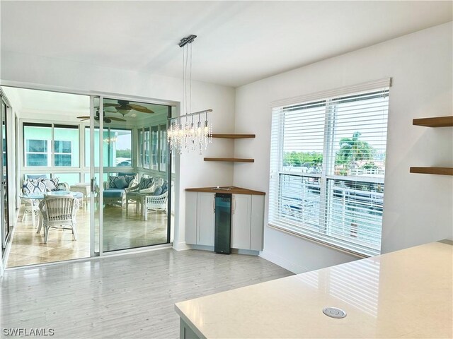 interior space with wine cooler, hanging light fixtures, and ceiling fan with notable chandelier