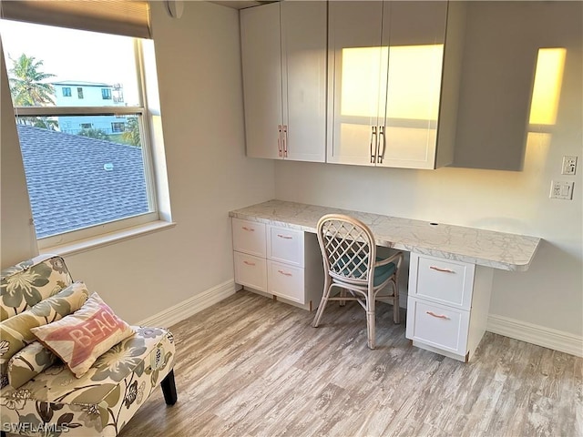 office area with light wood-style flooring, baseboards, and built in desk