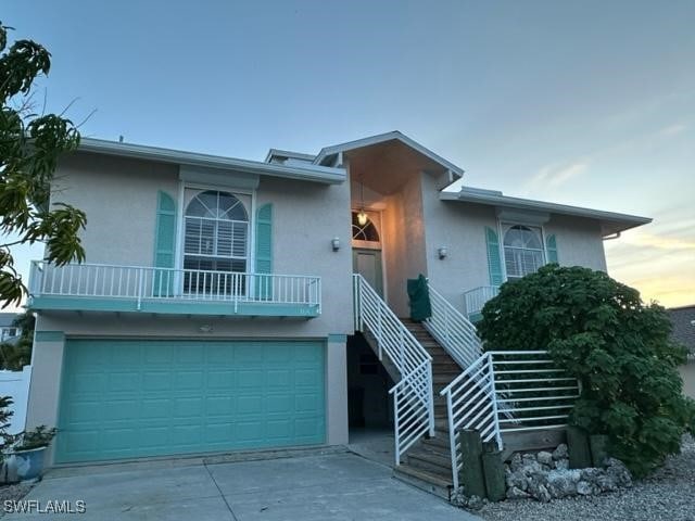 view of front of house featuring a garage, driveway, stairs, and stucco siding