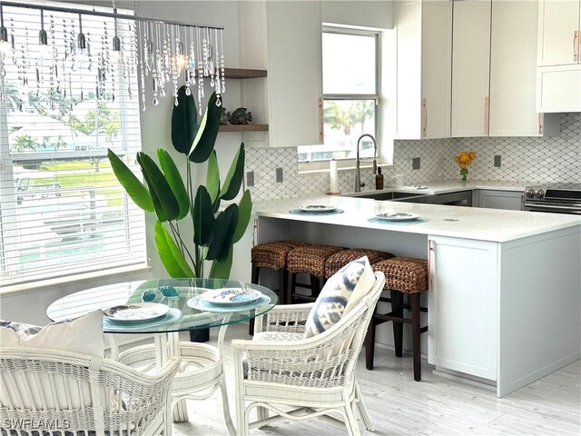 kitchen featuring light countertops, a sink, decorative backsplash, and open shelves