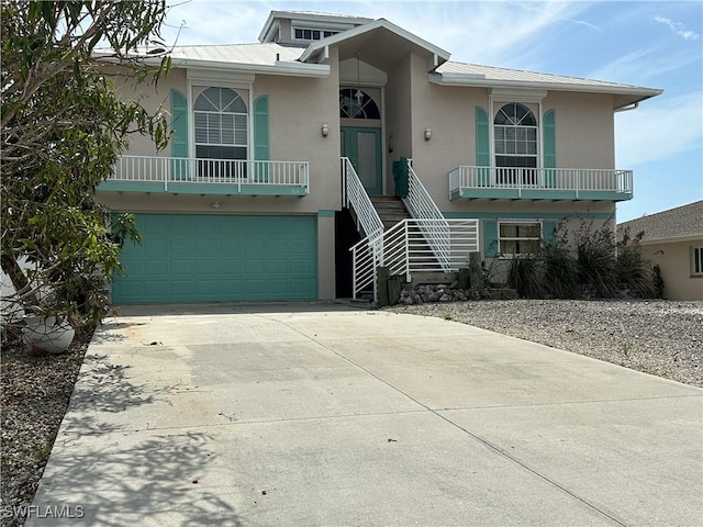 view of front facade featuring an attached garage, metal roof, concrete driveway, and stucco siding