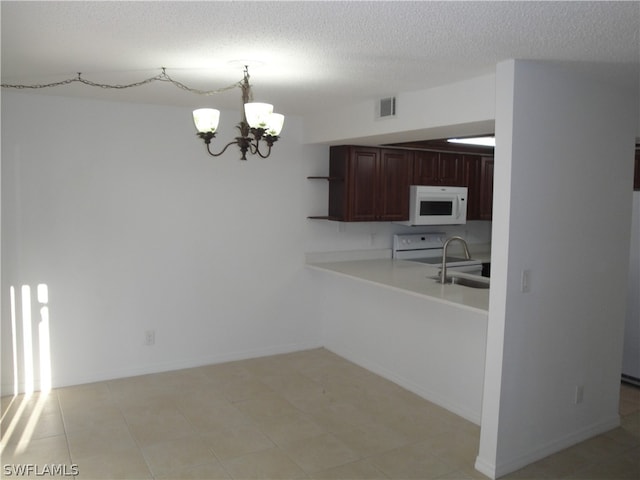 kitchen with hanging light fixtures, light tile flooring, white appliances, an inviting chandelier, and a textured ceiling