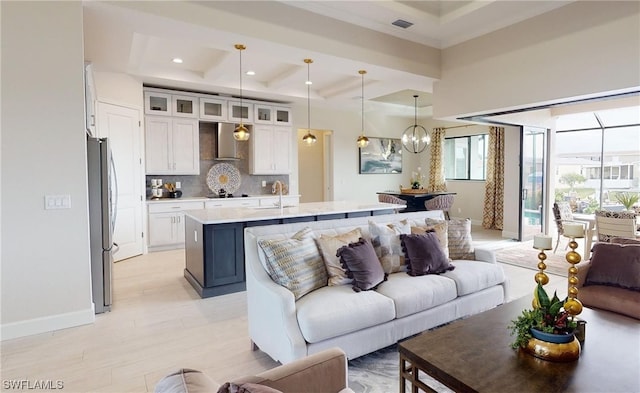 living room with an inviting chandelier, a raised ceiling, and sink