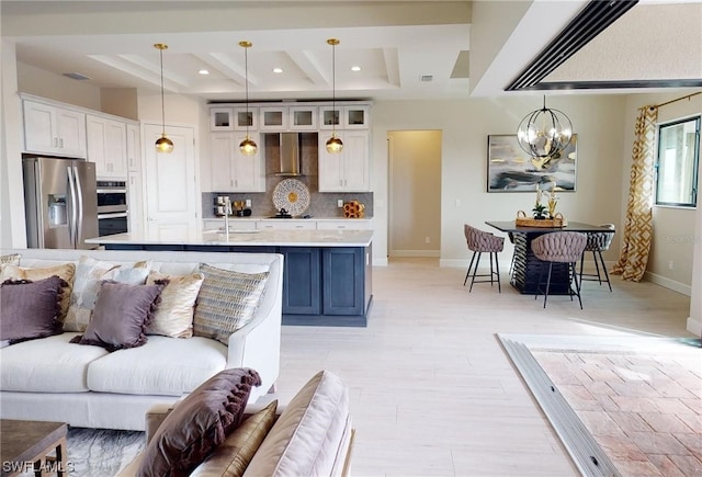 living room featuring a chandelier, a raised ceiling, and sink