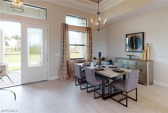 dining area featuring an inviting chandelier, a raised ceiling, a healthy amount of sunlight, and ornamental molding