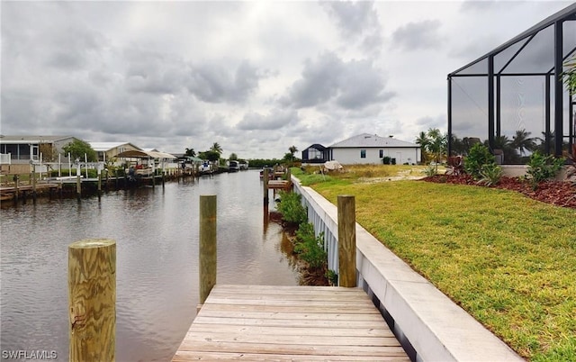 view of dock featuring a water view, a lanai, and a lawn