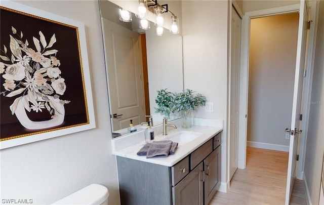 bathroom with toilet, vanity with extensive cabinet space, and hardwood / wood-style flooring