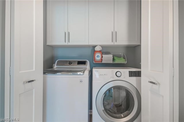 clothes washing area featuring cabinets and washer and dryer