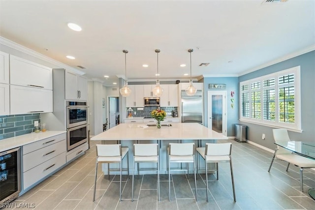 kitchen featuring pendant lighting, backsplash, wine cooler, appliances with stainless steel finishes, and a large island