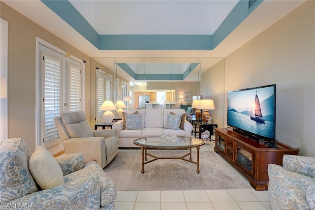 living room with a raised ceiling and light tile patterned floors