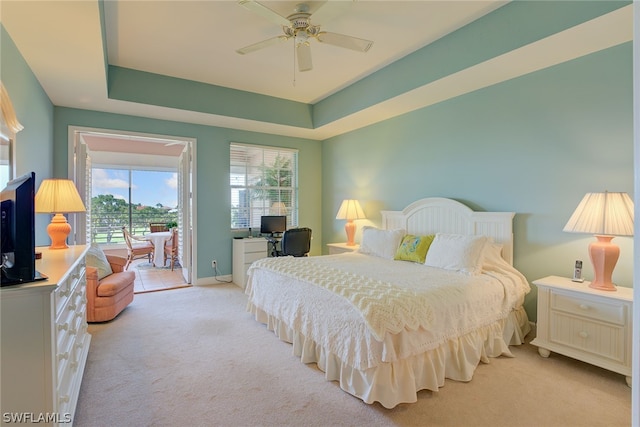 bedroom with a raised ceiling, access to exterior, ceiling fan, and light colored carpet