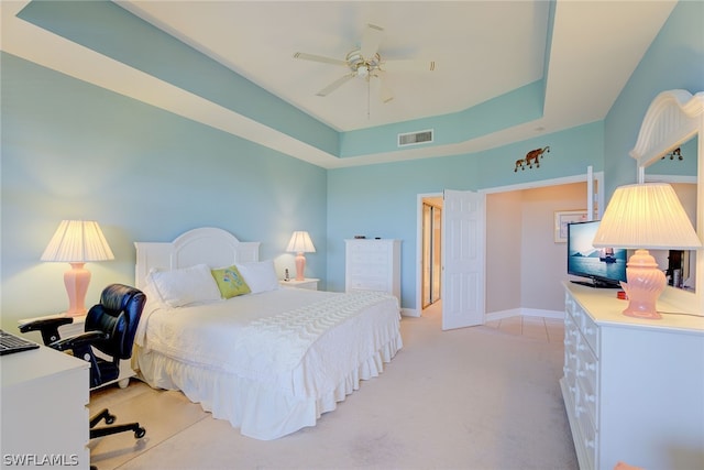 carpeted bedroom featuring a tray ceiling and ceiling fan