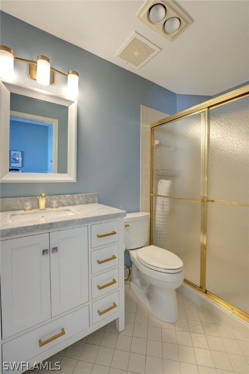 bathroom featuring tile patterned flooring, vanity, toilet, and a shower with door