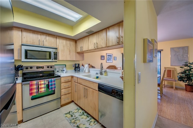 kitchen featuring light tile floors, appliances with stainless steel finishes, light brown cabinetry, and sink