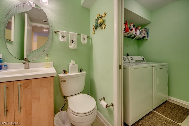 bathroom with washing machine and clothes dryer, toilet, vanity with extensive cabinet space, and tile flooring