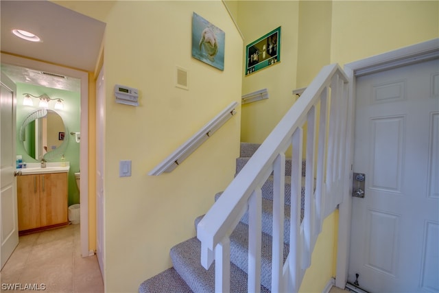 staircase featuring light tile floors and sink