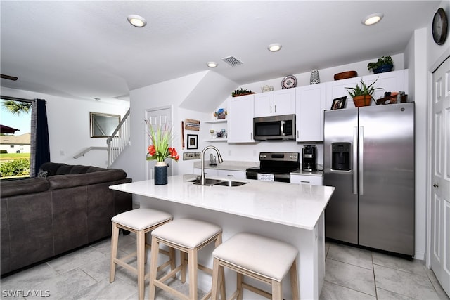 kitchen featuring stainless steel appliances, light tile flooring, a center island with sink, white cabinets, and sink