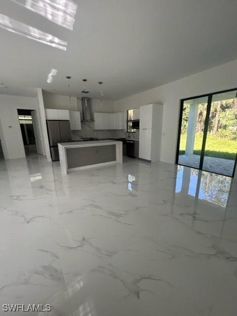 kitchen featuring white cabinets, stainless steel fridge, a kitchen island, and wall chimney range hood