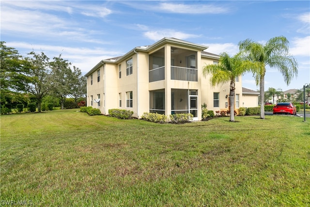 rear view of house with a lawn and a balcony