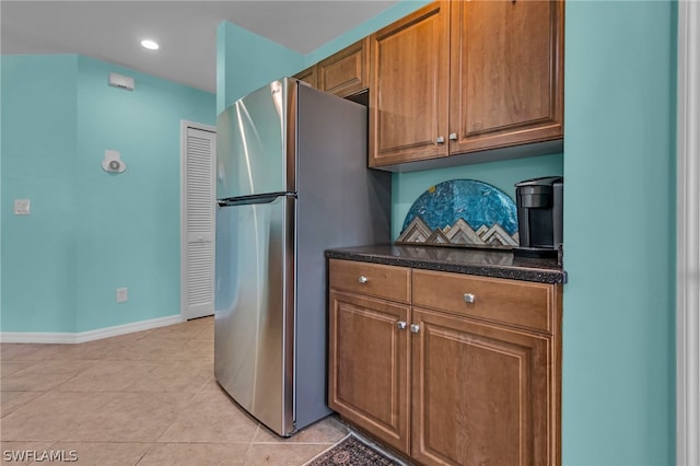 kitchen with decorative backsplash, light tile patterned flooring, and stainless steel fridge