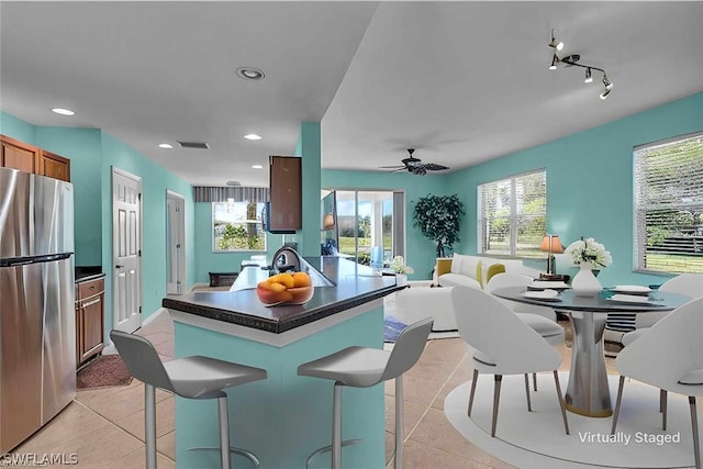 kitchen featuring a wealth of natural light, light tile patterned floors, and stainless steel fridge