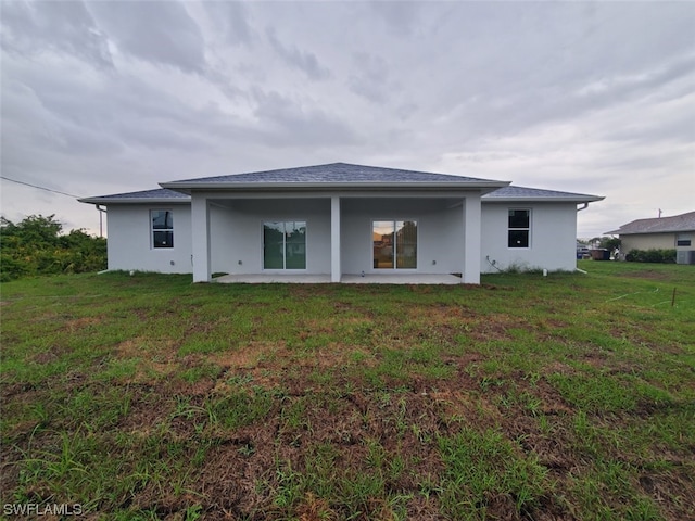 back of property featuring a lawn and a patio area