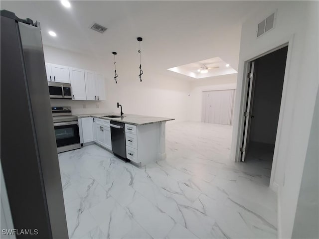 kitchen with pendant lighting, white cabinets, sink, appliances with stainless steel finishes, and kitchen peninsula