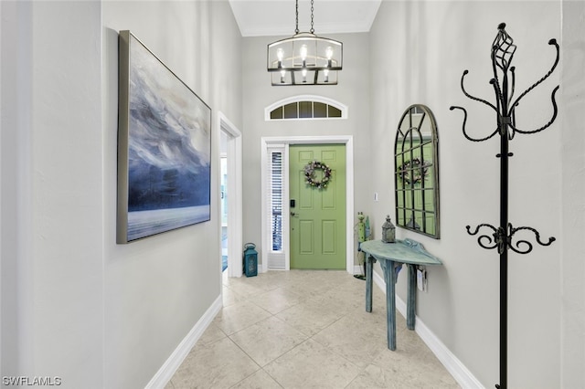 tiled foyer entrance with ornamental molding and a chandelier