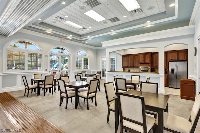 dining space with crown molding, a raised ceiling, and french doors