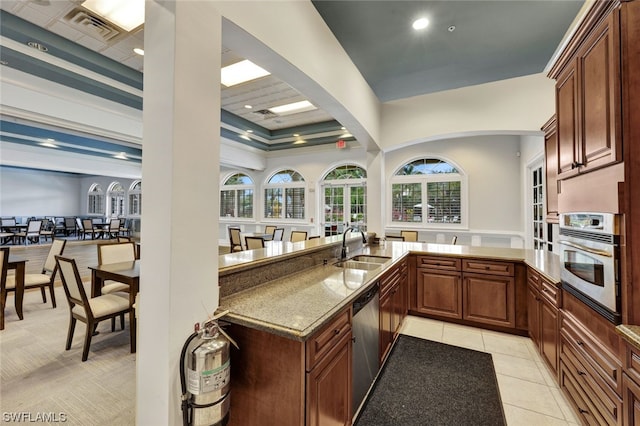 kitchen featuring sink, light tile patterned floors, appliances with stainless steel finishes, light stone countertops, and kitchen peninsula