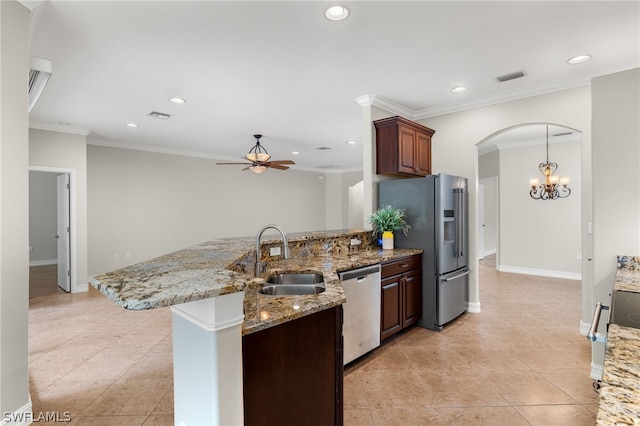 kitchen with appliances with stainless steel finishes, ceiling fan with notable chandelier, sink, ornamental molding, and light stone countertops