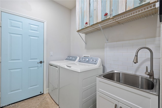 laundry area with separate washer and dryer, sink, light tile patterned floors, and cabinets