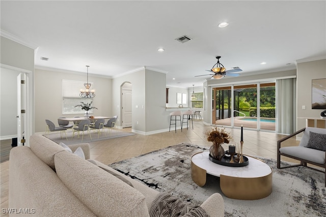 tiled living room with ceiling fan with notable chandelier and ornamental molding