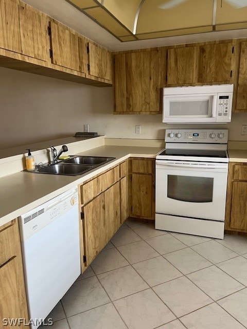 kitchen featuring white appliances, sink, and light tile floors