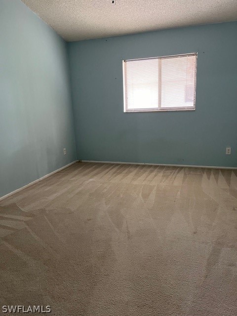 spare room featuring carpet flooring and a textured ceiling