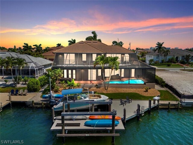 back house at dusk with a patio, a water view, and a lanai