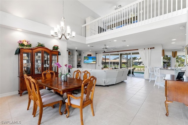 dining space with ceiling fan with notable chandelier, light tile patterned floors, and a high ceiling