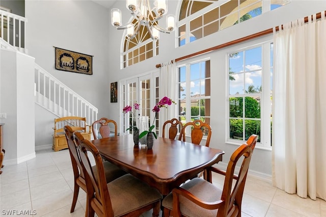 dining room featuring light tile patterned flooring, french doors, a high ceiling, and a chandelier