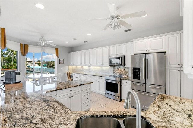 kitchen featuring white cabinets, stainless steel appliances, light stone countertops, and sink