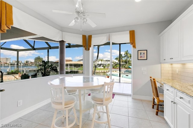 tiled dining area with a water view and ceiling fan