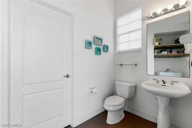 half bath with toilet, baseboards, and wood finished floors